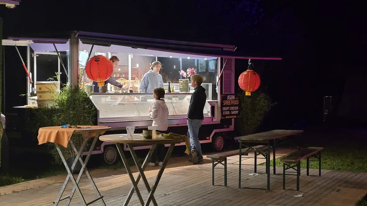 Asian streetfoodwagen met rode lampionnen tijdens een avondevenement