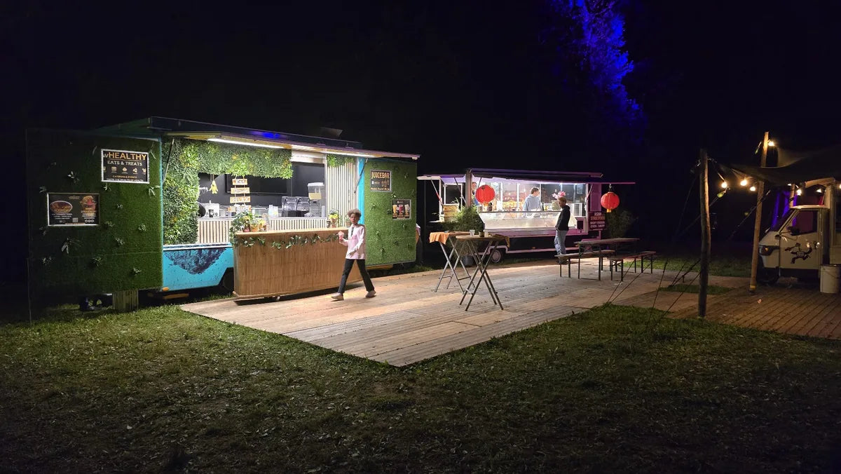 Groene wHealthy-foodtruck naast de Asian streetfoodwagen bij avond