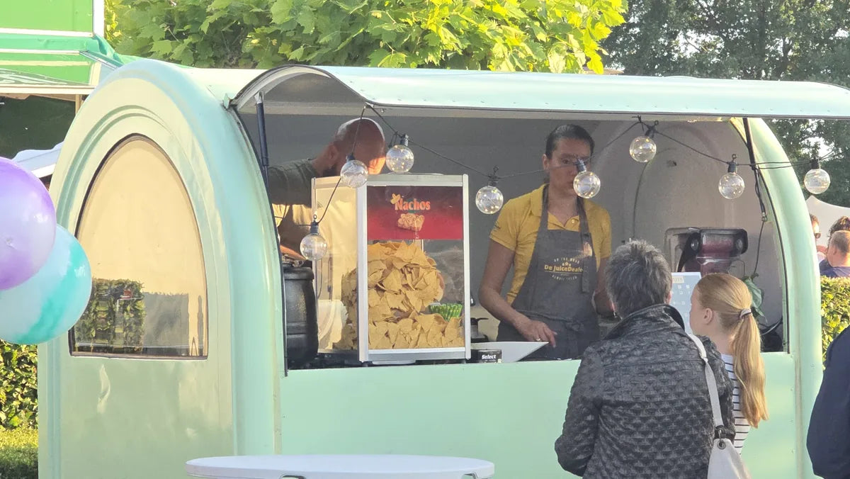 Mintgroene foodtrailer met nachos en verlichting bij de uitgifte