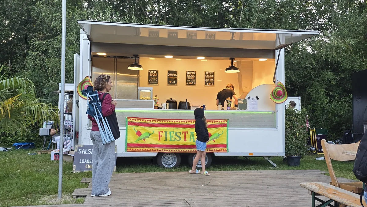 Witte foodtruck met nachos, churros en kleurrijke feestdecoratie